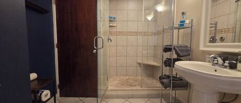 Un baño con ducha envuelta en cristal, un lavabo blanco y un inodoro.