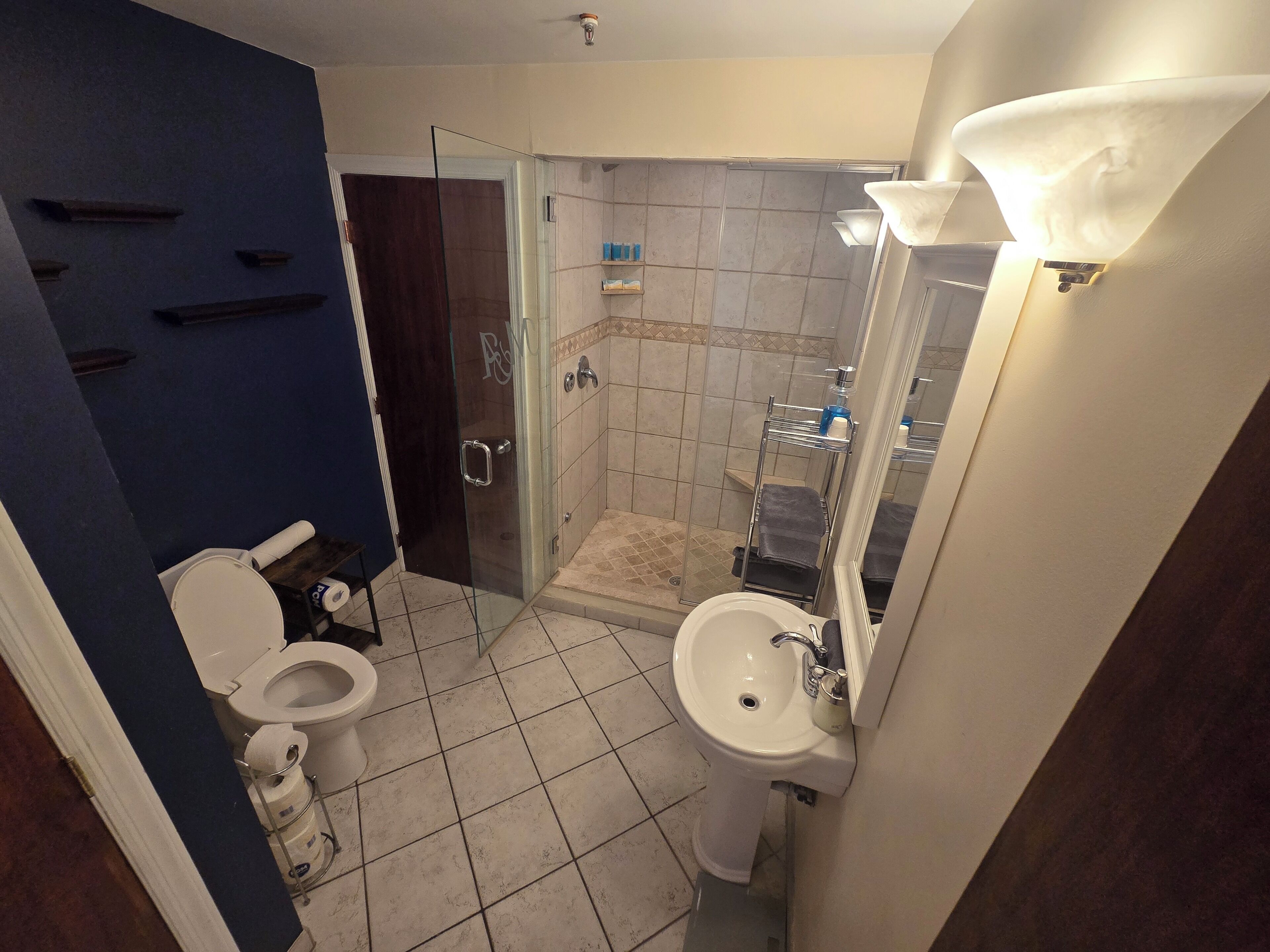 A bathroom with a toilet, sink, shower, and glass door.