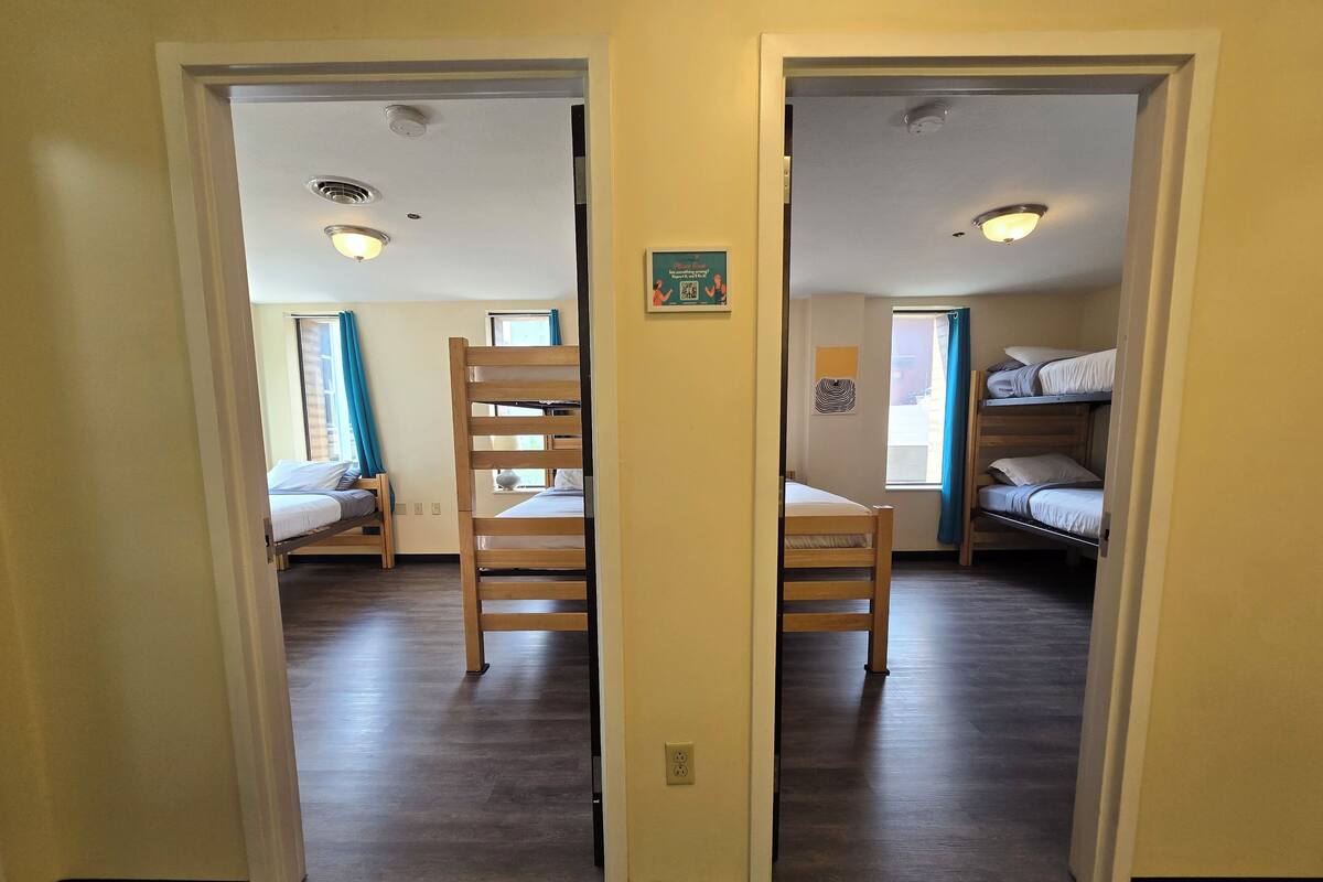 A hallway with wooden floors, bunk beds, and a door with a small picture frame.