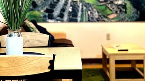 A dining area with a table, chairs, a vase with green plants, a painting of a mountainous landscape, and a hanging light fixture. - Stay Pittsburgh (Pittsburgh)