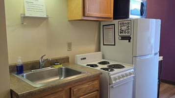 A kitchen with wooden cabinets, a stainless steel sink, a stove, and a refrigerator.