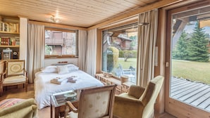 A wooden room with a bed, chairs, a table, and a large window. - Appartement Lanura - Welkeys (Megève)