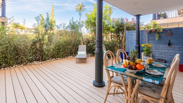 A wooden deck with a glass table set for dining, surrounded by wicker chairs and a lounge chair. - Appartement du Brost - Résidence le clôt des Sarments - Welkeys (La Croix-Valmer)