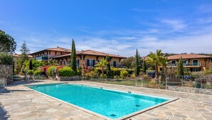 A rectangular swimming pool with stone tiles, surrounded by a stone wall and a fence. - Appartement du Brost - Résidence le clôt des Sarments - Welkeys (La Croix-Valmer)