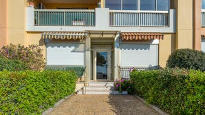 A building with a gated entrance, a small porch, and a gravel pathway leading to the door. - Appartement Rivage - Welkeys (Cagnes-sur-Mer)