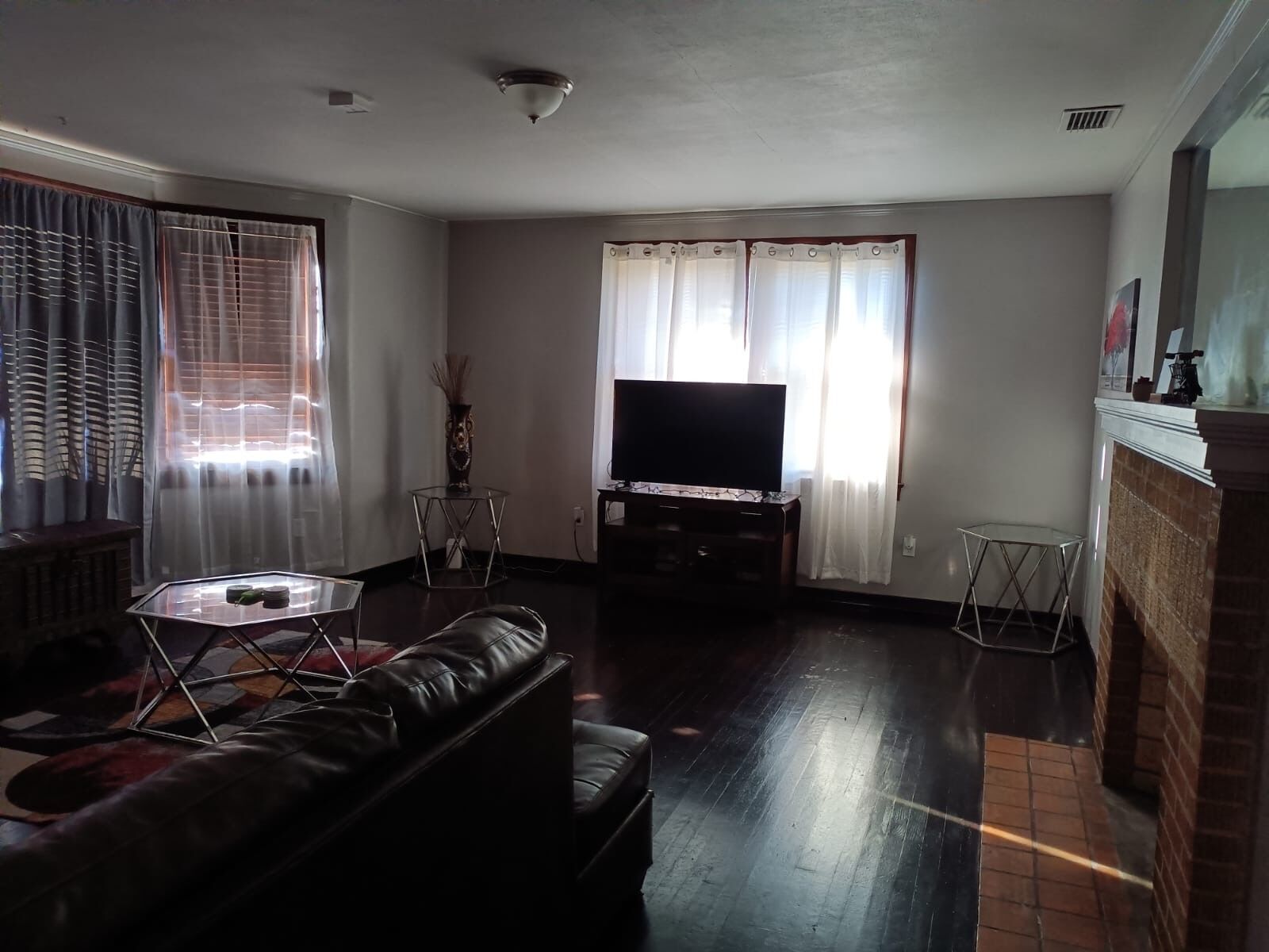 A living room with a leather sofa, a glass coffee table, a flat-screen TV, and a fireplace.
