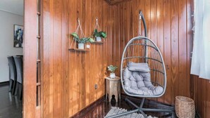 A cozy room with wooden paneling, a hanging chair, and potted plants. - Comfy pet friendly home in JAX mins to downtown (Jacksonville)