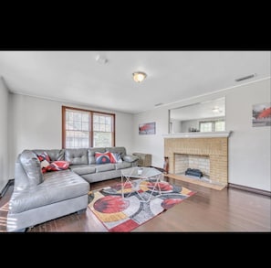 A living room with a sectional sofa, a fireplace, and a large window.