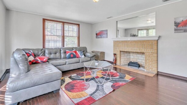 A living room with a sectional sofa, a fireplace, and a large window. - Comfy pet friendly home in JAX mins to downtown (Jacksonville)