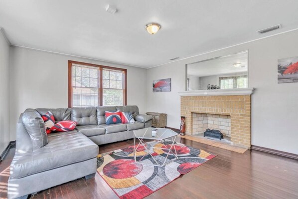 A living room with a sectional sofa, a fireplace, and a large window. - Comfy pet friendly home in JAX mins to downtown (Jacksonville)