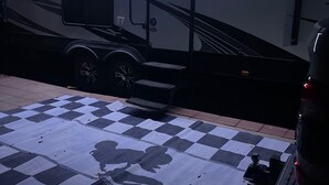 Un grand camping-car orné du logo « TORQUE », un espace abrité avec un tapis à carreaux, et un autre véhicule garé à proximité.