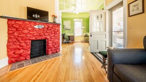Un salon doté d’une cheminée en pierre rouge, d’un plancher en bois et d’un mur vert.