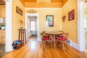A dining area with a wooden table and chairs, a vase with flowers, and a painting on the wall. - Mt Washington House (Colorado Springs)