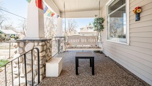 Un porche abrité avec un mur en pierre, un banc et une table.