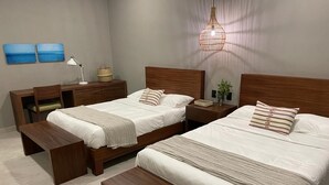 A hotel room with two beds, a desk, a chair, and a bench.