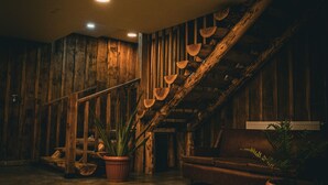 Een rustiek interieur met een houten trap, potplanten en een betonnen vloer.