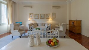 A spacious living room with a white sofa set, two armchairs, a coffee table, and a fruit bowl on a white table. - Raso cozy penthouse near the Duomo (Firenze)