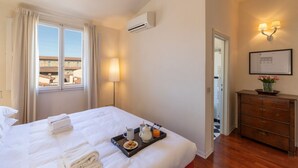 Quarto de hotel com uma cama, uma bandeja com itens de café da manhã, um penteado e uma janela com cortinas.