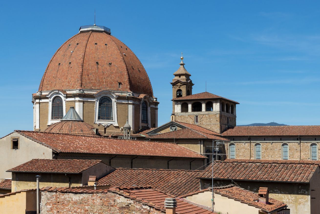 Un edificio histórico con una cúpula destacada y un campanario, rodeado de arquitectura tradicional.