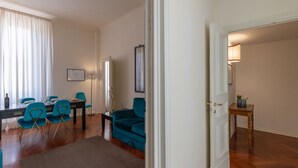 A modern living room with a dining area, featuring a sofa, chairs, a coffee table, and a dining table set for four. - Seta spacious apartment next to the Duomo (Firenze)