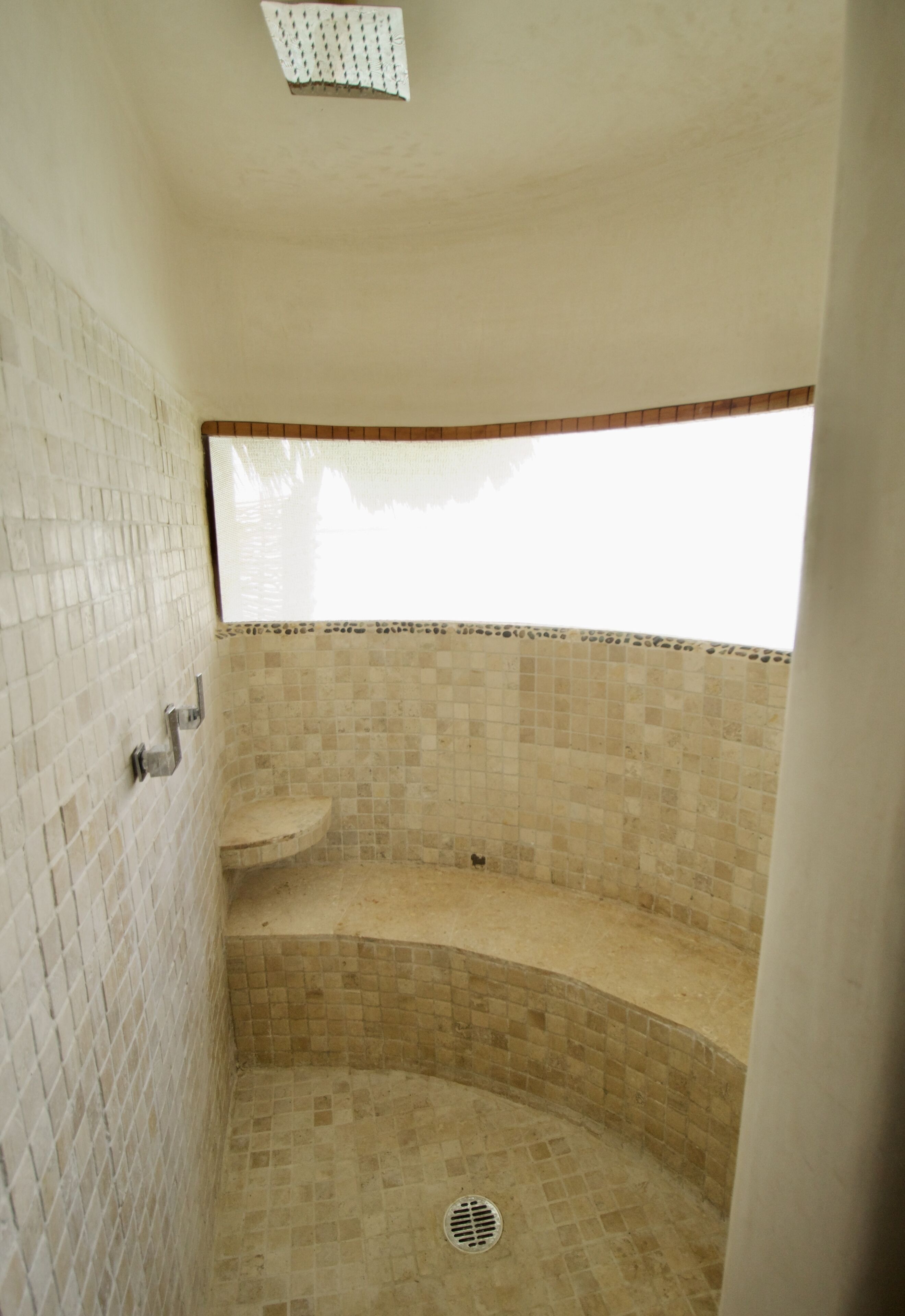 A small, enclosed shower area with tiled walls and a drain.