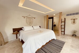 A well-lit bedroom with a large bed, a bedside table, a wall-mounted macrame decoration, and a wooden ladder.