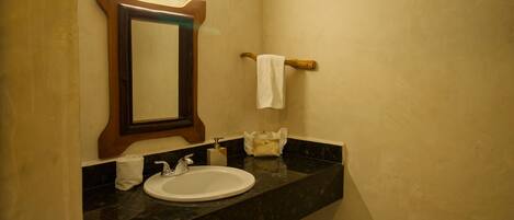 A bathroom with a sink, mirror, towel rack, and a soap dispenser.