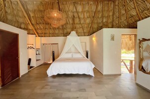 Una habitación con una cama, techo de madera, una puerta y un banco.