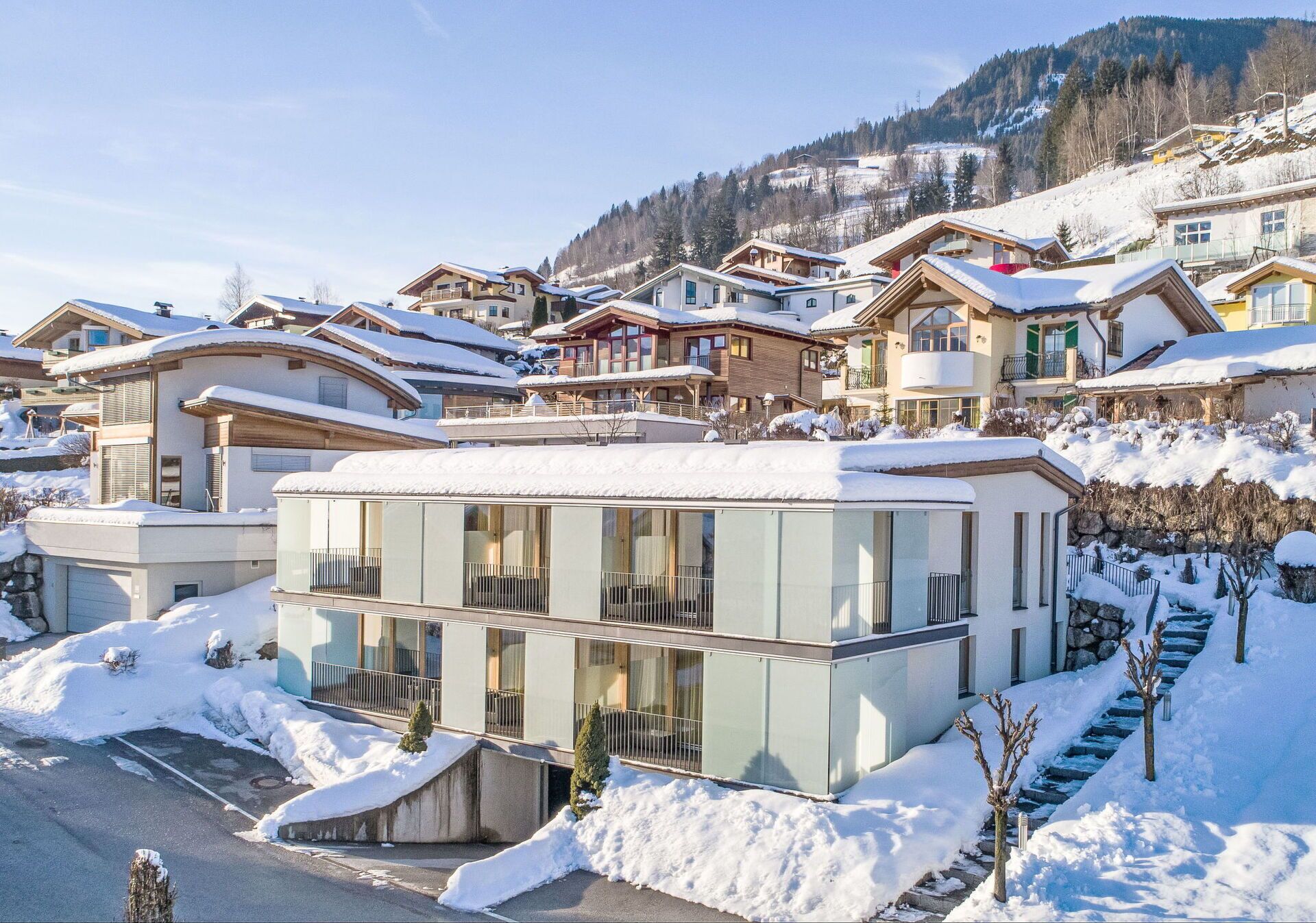 A modern ski resort with snow-covered buildings and a clear view of the surrounding mountains.
