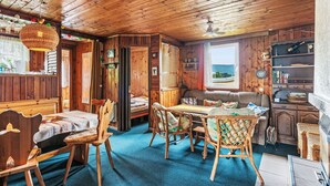 En mysig stuga med en matplats, en soffa och utsikt över naturen.