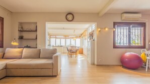 Ein geräumiges Wohnzimmer mit einer Couch, einem Essbereich und einer Küche im Hintergrund.