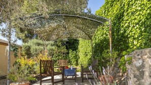 Eine Terrassengruppe im Freien mit einer Pergola, Steinstufen und Holzmöbeln.