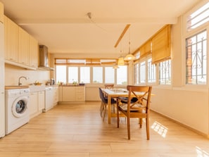Cozinha espaçosa com área de refeições, janelas amplas e máquina de lavar.