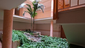 A multi-level atrium with a central garden area featuring a palm tree, various plants, and a stone pathway. - Beautiful apartment for 4 people with pool, A/C, TV and terrace (Sant Carles De La Ràpita)