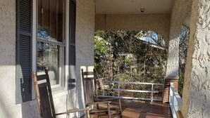 Eine überdachte Veranda mit Holzschaukelstühlen und einem weißen Geländer.