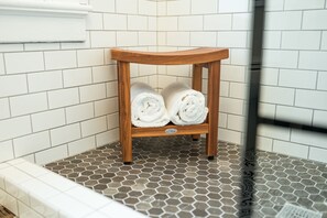 Un bagno angolare con un porta asciugamani in legno che contiene due asciugamani arrotolati.