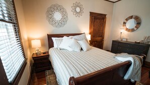 Ein Schlafzimmer mit einem hölzernen Bett, zwei Wandleuchten, einer Kommode und einem großen Spiegel.