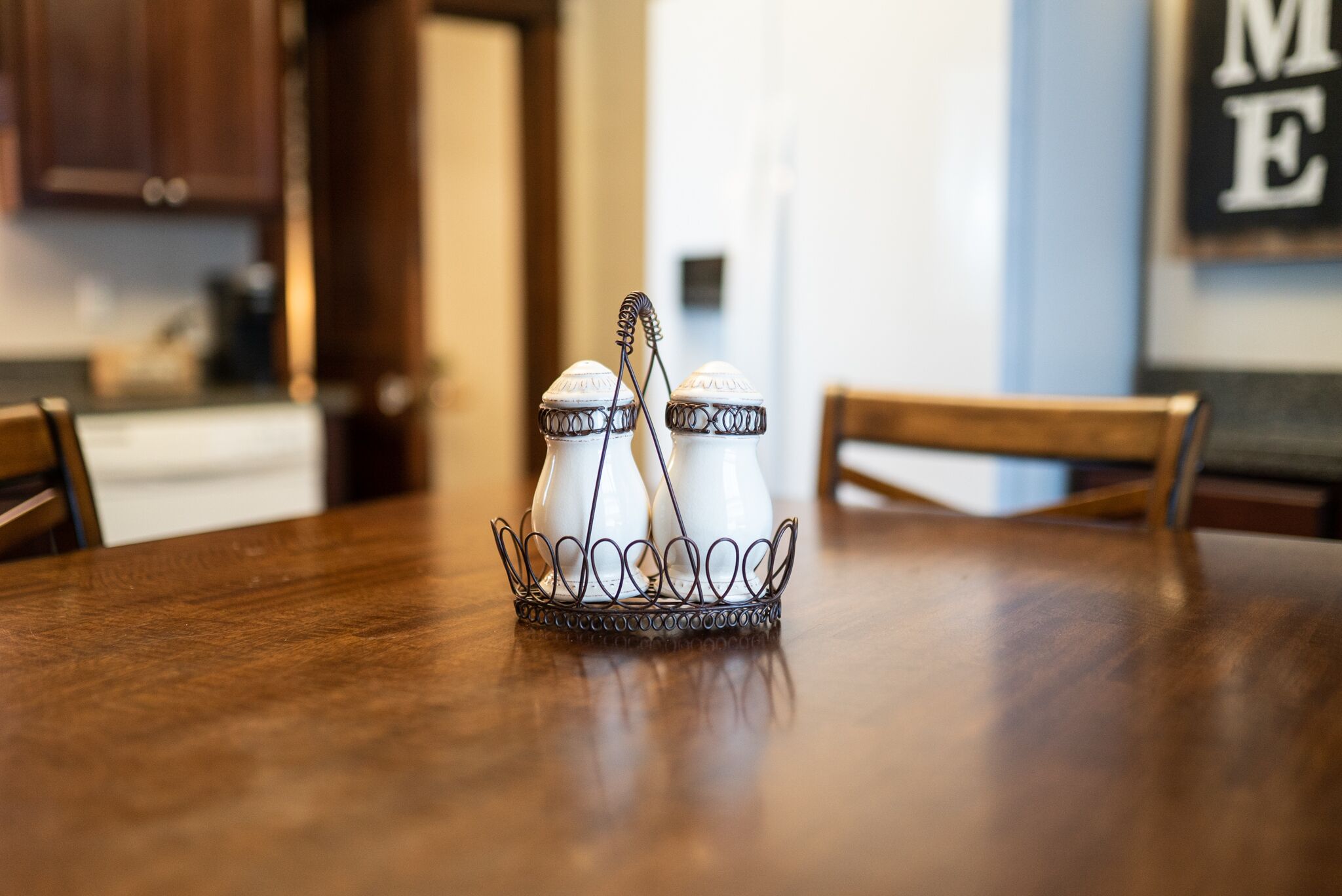 A dining table with a salt and pepper shaker set in a wire basket.