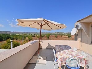 Une terrasse avec une table et des chaises, un parasol et une vue sur un paysage rural.