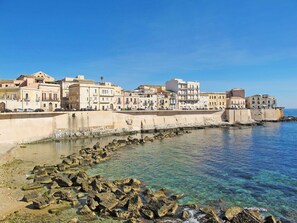 Une ville côtière avec des bâtiments qui bordent le front de mer, une eau d’un bleu limpide et une côte rocheuse.