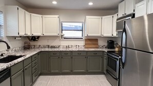 A kitchen with light green cabinets, a stainless steel refrigerator, and a window with blinds. - Lakeside Retreat with Dock/Porch/Firepit/Beach (Fort McCoy)