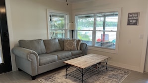 A living room with a grey sofa, a wooden coffee table, and a patterned rug. - Lakeside Retreat with Dock/Porch/Firepit/Beach (Fort McCoy)