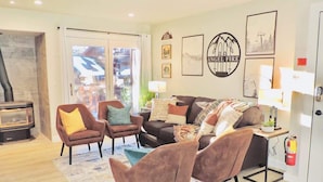A modern living room with a fireplace, comfortable seating, and a fire extinguisher on the wall. - Modern getaway! Relax, bike, hike, and shred! (Angel Fire)