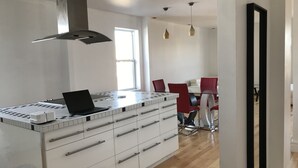 A modern kitchen with a central island, white cabinetry, and a laptop on the countertop. - Spacious 2 br apartment in the heart of Montreal (Montréal)
