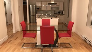 A modern kitchen with a central island, stainless steel appliances, and a dining area with red chairs and a glass table. - Spacious 2 br apartment in the heart of Montreal (Montréal)