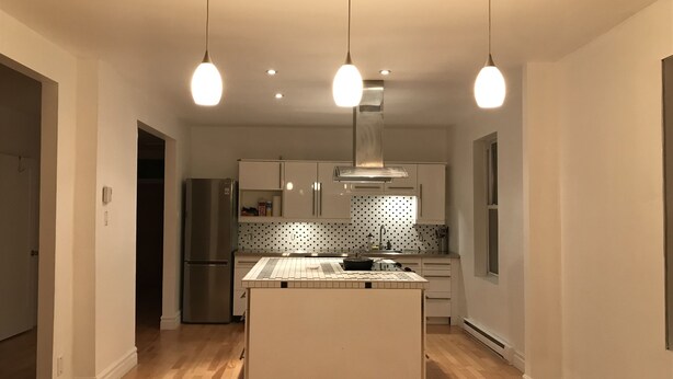 A modern kitchen with a central island, pendant lighting, and a stainless steel refrigerator. - Spacious 2 br apartment in the heart of Montreal (Montréal)