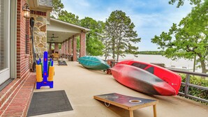 A covered outdoor area with kayaks and paddleboards, a door, and a view of a lake. - Dock & Game Room: Alvarado Lake Getaway! (Alvarado)