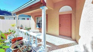 A covered patio area with potted plants and a white railing. - Relaxing 3 Bedroom Pool Home (Tampa)