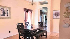 A dining area with a dark wooden table, four chairs, and a bench. There is a chandelier above the table, and a framed picture on the wall. - Relaxing 3 Bedroom Pool Home (Tampa)