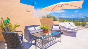 An outdoor patio with wicker furniture, a glass table, and a potted plant. - CAN VIDAL - Cozy House with Private Pool and Free WiFi (Campanet)